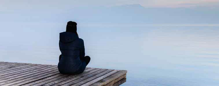 woman meditating on a dock