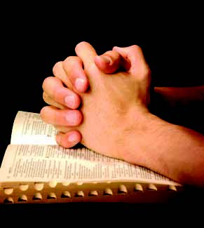 hands folded above Bible