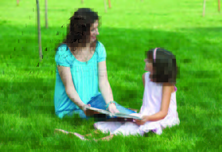 mother and daughter reading in grass